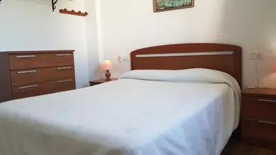 a bedroom with a white bed and a dresser at Apartamento en primera línea de playa en 2ª planta in Novo Sancti Petri