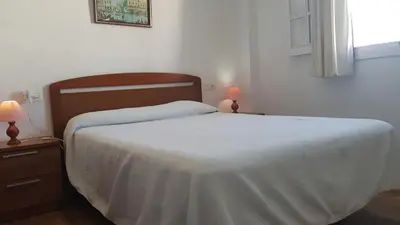 a bedroom with a bed with a white blanket on it at Apartamento en primera línea de playa en 2ª planta in Novo Sancti Petri