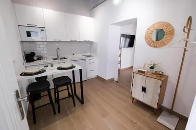 a kitchen with white cabinets and a table and chairs at La Zarzamora in Jerez de la Frontera