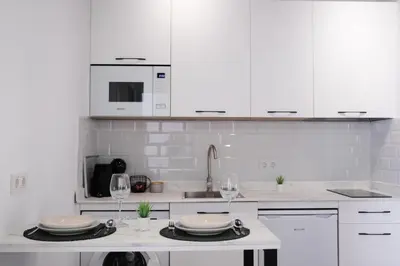 a white kitchen with white cabinets and wine glasses at La Zarzamora in Jerez de la Frontera