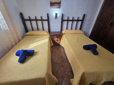 two beds in a room with blue slippers on them at Casas el Palomar in Conil de la Frontera