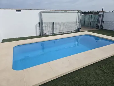 a large blue swimming pool in a yard at Casas el Palomar in Conil de la Frontera