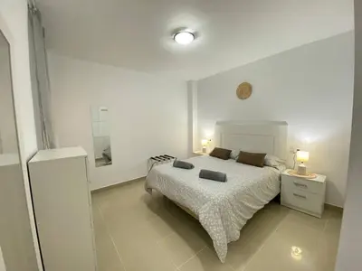 a white bedroom with a bed and two lamps at Banda Playa Home, Pleno Centro in Sanlúcar de Barrameda