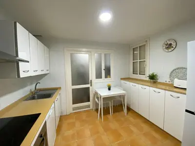 a kitchen with white cabinets and a small white table at Banda Playa Home, Pleno Centro in Sanlúcar de Barrameda