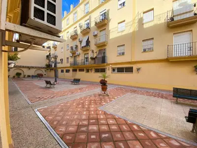 an empty courtyard of a large building with benches at Banda Playa Home, Pleno Centro in Sanlúcar de Barrameda