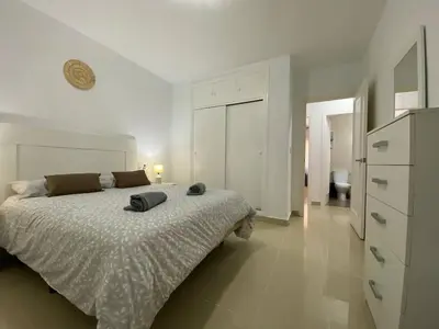 a white bedroom with a bed and a dresser at Banda Playa Home, Pleno Centro in Sanlúcar de Barrameda
