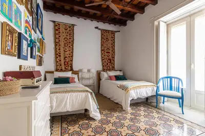 a bedroom with two beds and a blue chair at NUEVO-NEW Casa Palacio M anuela in Jerez de la Frontera