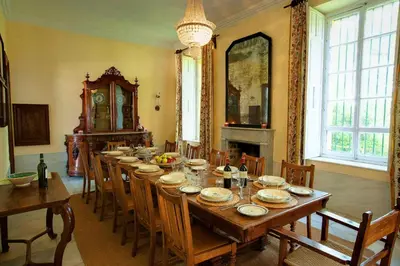a dining room with a long table with chairs and a clock at Hacienda La Parrilla Alta in Arcos de la Frontera