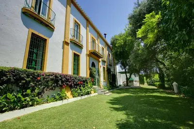 a large yellow building with a yard with grass and flowers at Hacienda La Parrilla Alta in Arcos de la Frontera