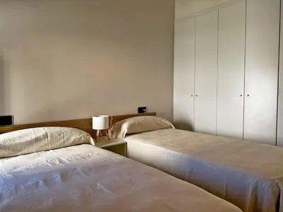 two beds in a room with white cabinets at La Solera de Jerez - Ole Solutions in Jerez de la Frontera