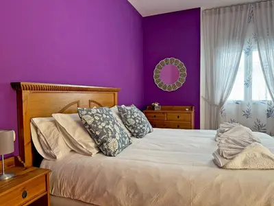 a bedroom with purple walls and a bed with pillows at Casa Luz de Azahar - Ole Solutions in Jerez de la Frontera