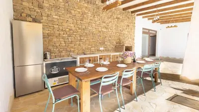 a kitchen with a wooden table with chairs and a refrigerator at Galdana Chiclana de la Frontera by Ruralidays in Chiclana de la Frontera