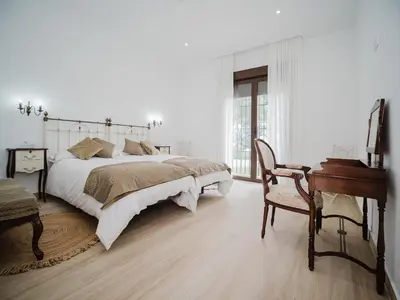 a white bedroom with a large bed and a desk at Casa Rural El Charruado in Sanlúcar de Barrameda