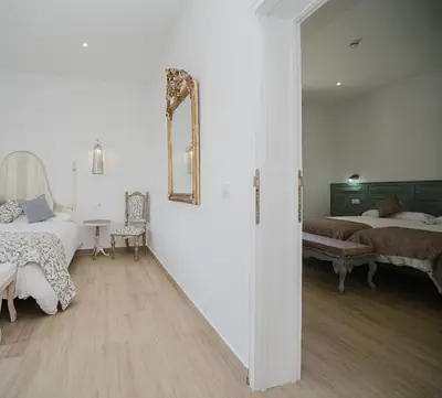 a white room with two beds and a mirror at Casa Rural El Charruado in Sanlúcar de Barrameda