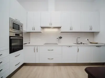 a white kitchen with white cabinets and a sink at Casa Rural El Charruado in Sanlúcar de Barrameda