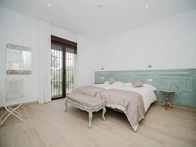 a white bedroom with a bed and a chair at Casa Rural El Charruado in Sanlúcar de Barrameda