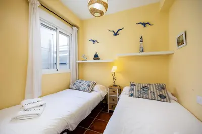 two beds in a room with birds on the wall at Bahia Beachfront Apartment in El Puerto de Santa María