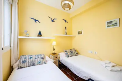 two beds in a room with birds on the wall at Bahia Beachfront Apartment in El Puerto de Santa María
