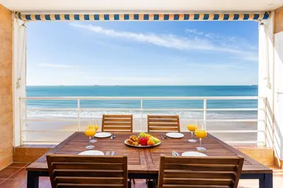 a table with a bowl of fruit and a view of the ocean at Bahia Beachfront Apartment in El Puerto de Santa María