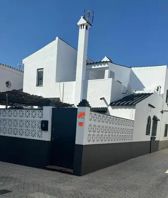 a white building with a gate and a tower at Dúplex a 700 m de la Playa de La Barrosa in Novo Sancti Petri