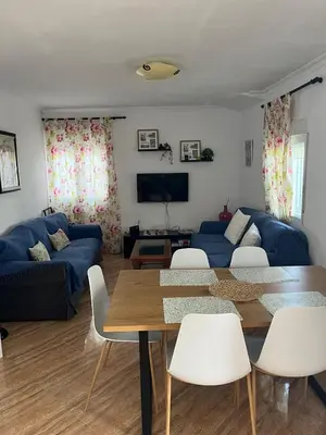 a living room with a table and a blue couch at Dúplex a 700 m de la Playa de La Barrosa in Novo Sancti Petri