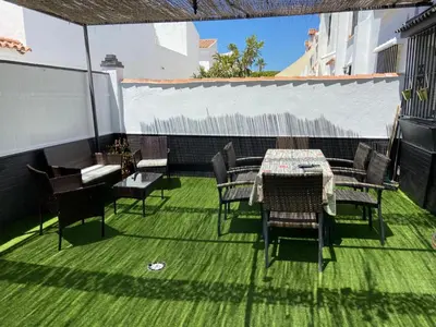 a patio with tables and chairs on a green lawn at Dúplex a 700 m de la Playa de La Barrosa in Novo Sancti Petri
