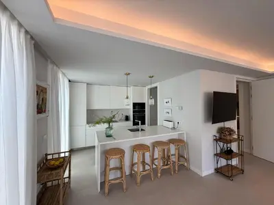 a kitchen with a white counter and stools at Apartamento RG Acciona Vistahermosa in El Puerto de Santa María