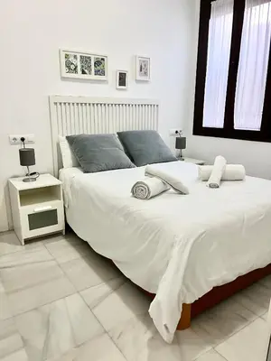 a bedroom with a large white bed and a window at La Bodega Suite - Parking gratis in Jerez de la Frontera