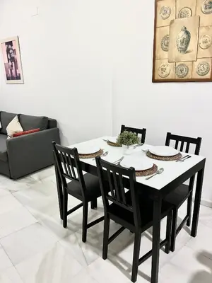 a dining room table with four chairs and a couch at La Bodega Suite - Parking gratis in Jerez de la Frontera