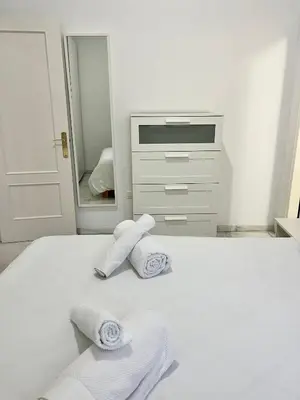 a white bedroom with two towels on a bed at La Bodega Suite - Parking gratis in Jerez de la Frontera