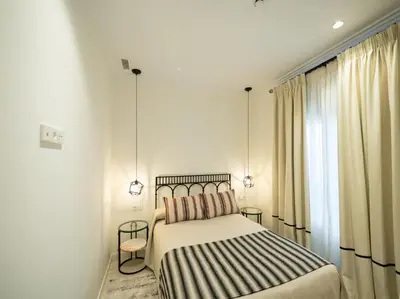 a bedroom with a bed and two tables and a window at AT La Maquinilla in Jerez de la Frontera