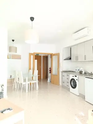 a white kitchen with a table and white appliances at piso LuMa in Jerez de la Frontera