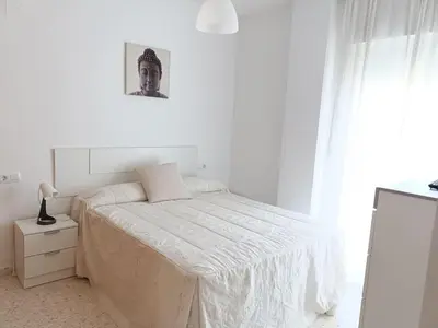 a white bedroom with a bed and a window at piso LuMa in Jerez de la Frontera