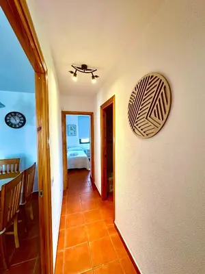 a hallway of a room with a bed and a clock on the wall at Apartamento La Barrosa - Aldea del Coto in Novo Sancti Petri
