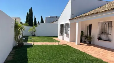 a courtyard of a white house with a lawn at Martiniano in Conil de la Frontera