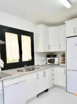 a white kitchen with white cabinets and a refrigerator at Martiniano in Conil de la Frontera