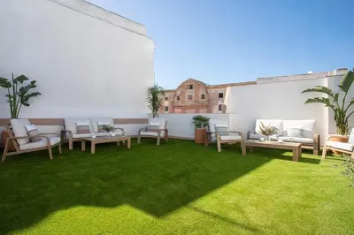 a patio with tables and chairs on a green lawn at Genteel Home Patrocinio Cádiz in Cádiz