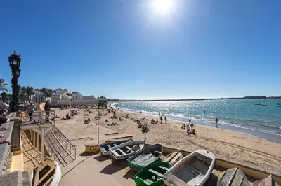 a beach with a lot of people and boats on it at Genteel Home Patrocinio Cádiz in Cádiz