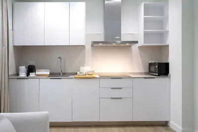a white kitchen with white cabinets and a microwave at Genteel Home Patrocinio Cádiz in Cádiz