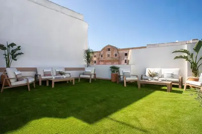 a patio with tables and chairs and grass at Genteel Home Patrocinio Cádiz in Cádiz