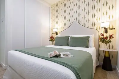 a bedroom with a bed with a book on it at Genteel Home Patrocinio Cádiz in Cádiz