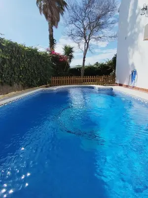 a large blue swimming pool in a yard at Casa Sebas in Conil de la Frontera