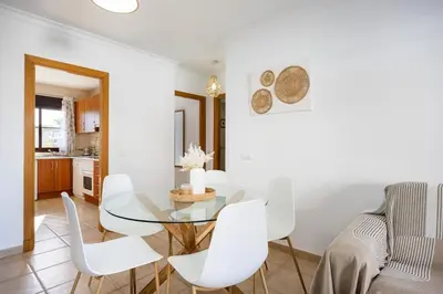 a dining room with a glass table and white chairs at Barrosa Beach Apartment - Chiclana de la Frontera in Novo Sancti Petri