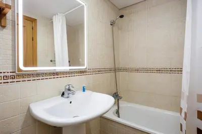 a bathroom with a sink and a mirror and a tub at Barrosa Beach Apartment - Chiclana de la Frontera in Novo Sancti Petri
