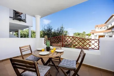 a patio with a wooden table and chairs on a balcony at Barrosa Beach Apartment - Chiclana de la Frontera in Novo Sancti Petri