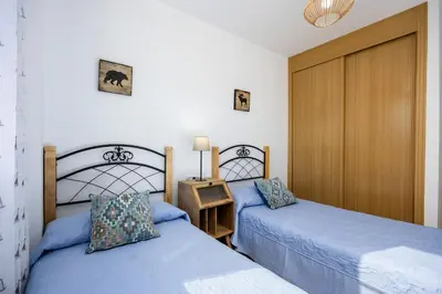 a bedroom with two beds and a wooden door at Barrosa Beach Apartment - Chiclana de la Frontera in Novo Sancti Petri