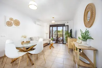 a dining room and living room with a table and chairs at Barrosa Beach Apartment - Chiclana de la Frontera in Novo Sancti Petri
