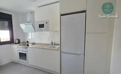 a white kitchen with a refrigerator and a sink at Apartamentos Turísticos Juan Grande by Sanlúcar Housing in Sanlúcar de Barrameda