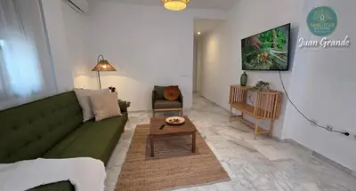 a living room with a green couch and a coffee table at Apartamentos Turísticos Juan Grande by Sanlúcar Housing in Sanlúcar de Barrameda