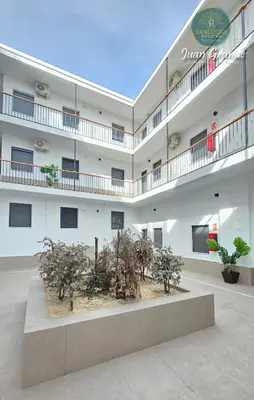 a large white building with trees in the courtyard at Apartamentos Turísticos Juan Grande by Sanlúcar Housing in Sanlúcar de Barrameda